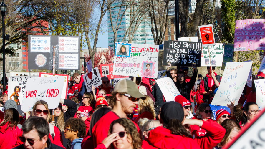 A group of the more than 20,000 striking teachers carrying picket signs at the Alberta Legislature
