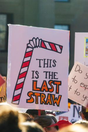 A protesting teacher holding a sign that says this is the last straw