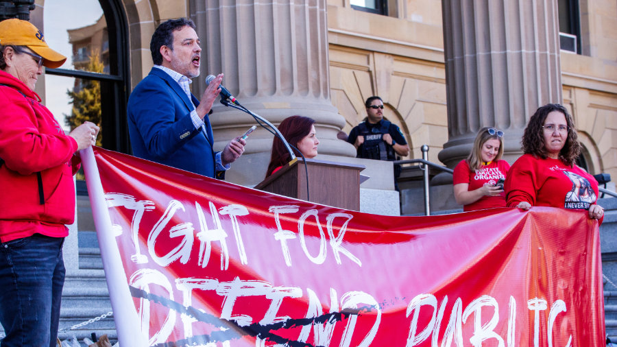 A picture of a speaker in front of a crowd of striking teachers.